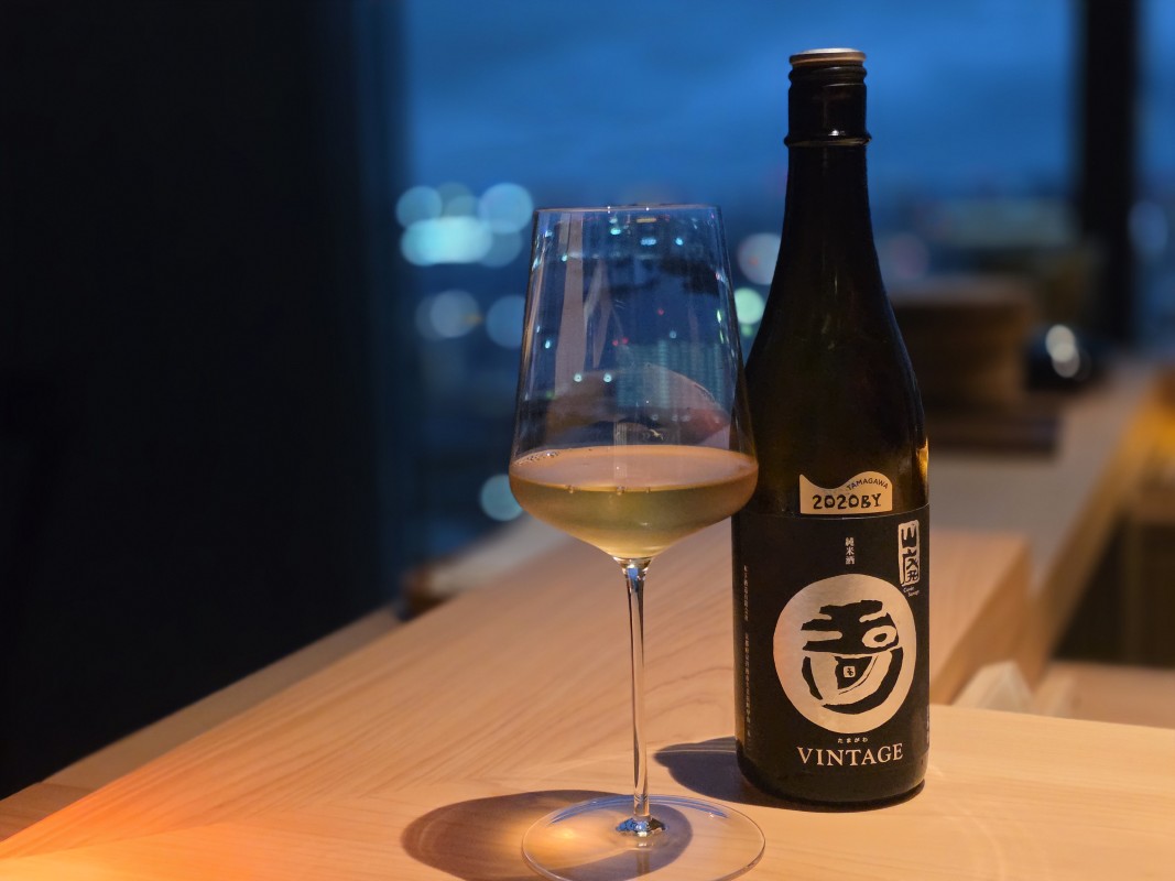 夜景を背景にした日本酒のボトルとワイングラス